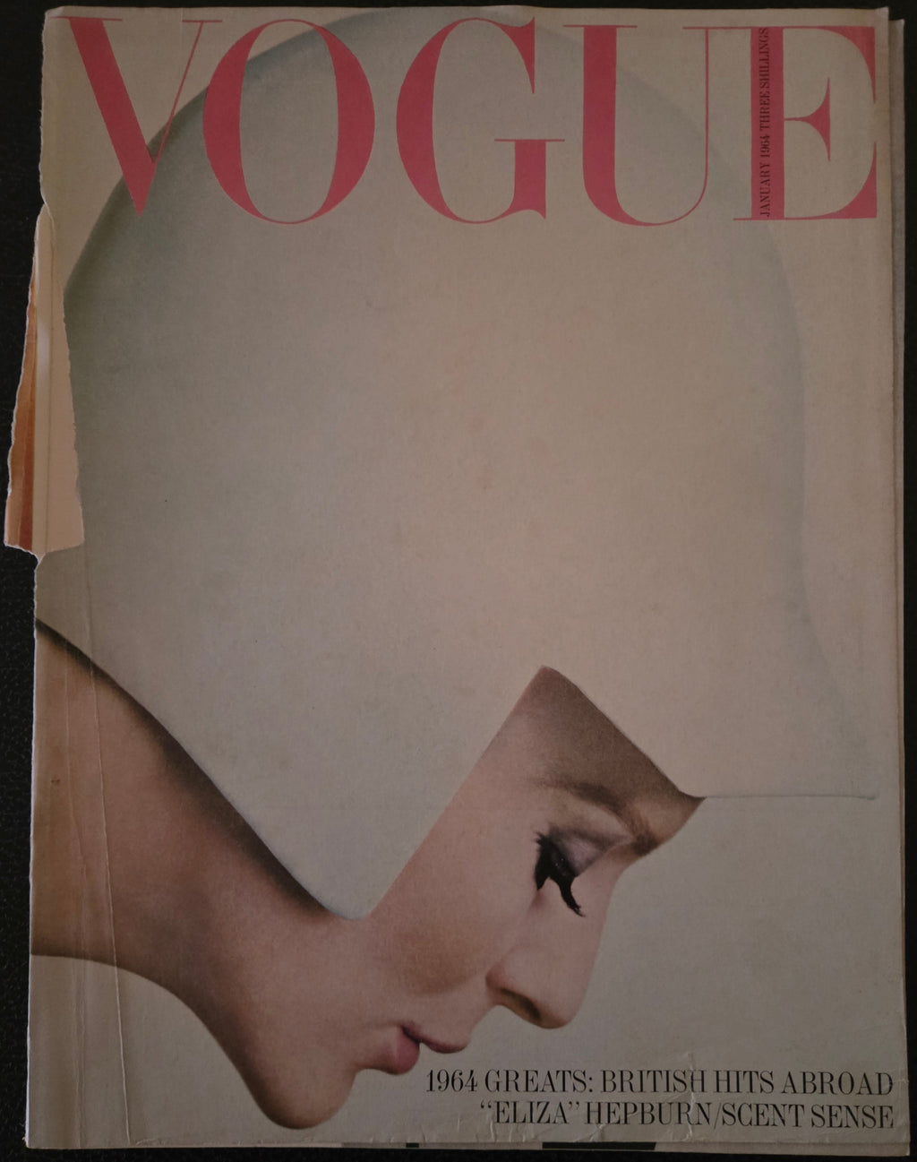 Vintage Vogue magazine cover with a woman wearing a white hat and the word 'Vogue' in pink.