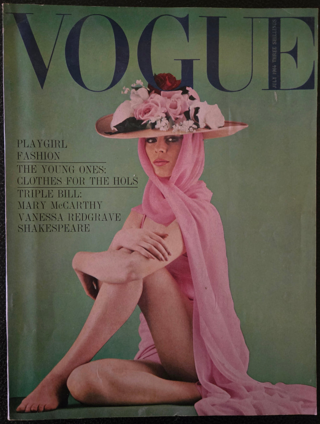 Vintage Vogue magazine cover with a model in a pink dress and hat on a green background