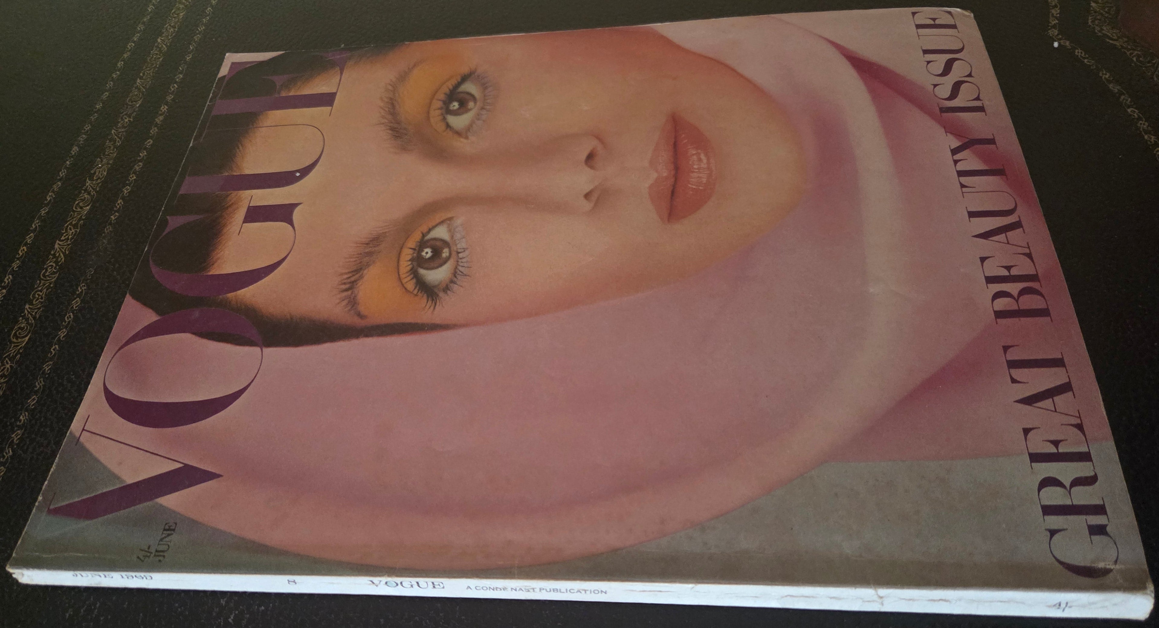 Vogue magazine cover with a model's face on a dark surface