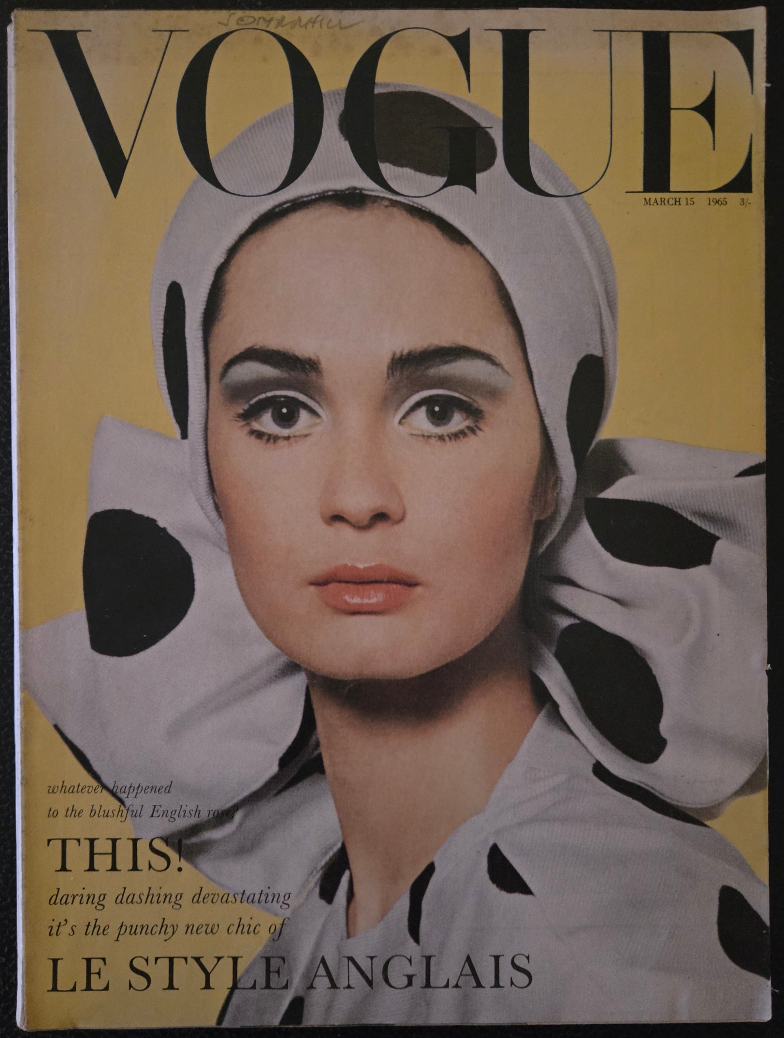 Vogue magazine cover with a woman's face and polka dot headscarf on a yellow background