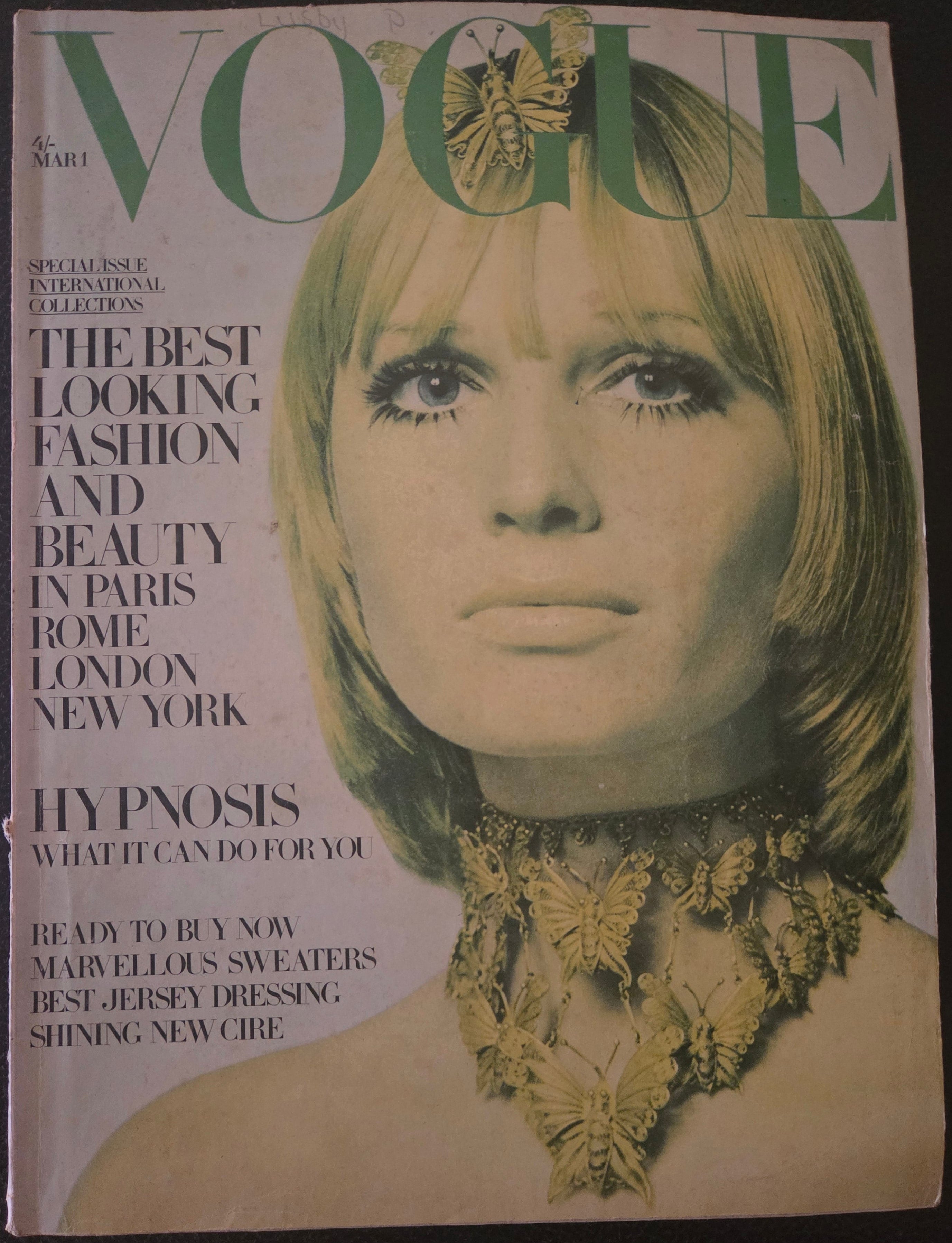 Vintage Vogue magazine cover with a model wearing a butterfly necklace on a dark background