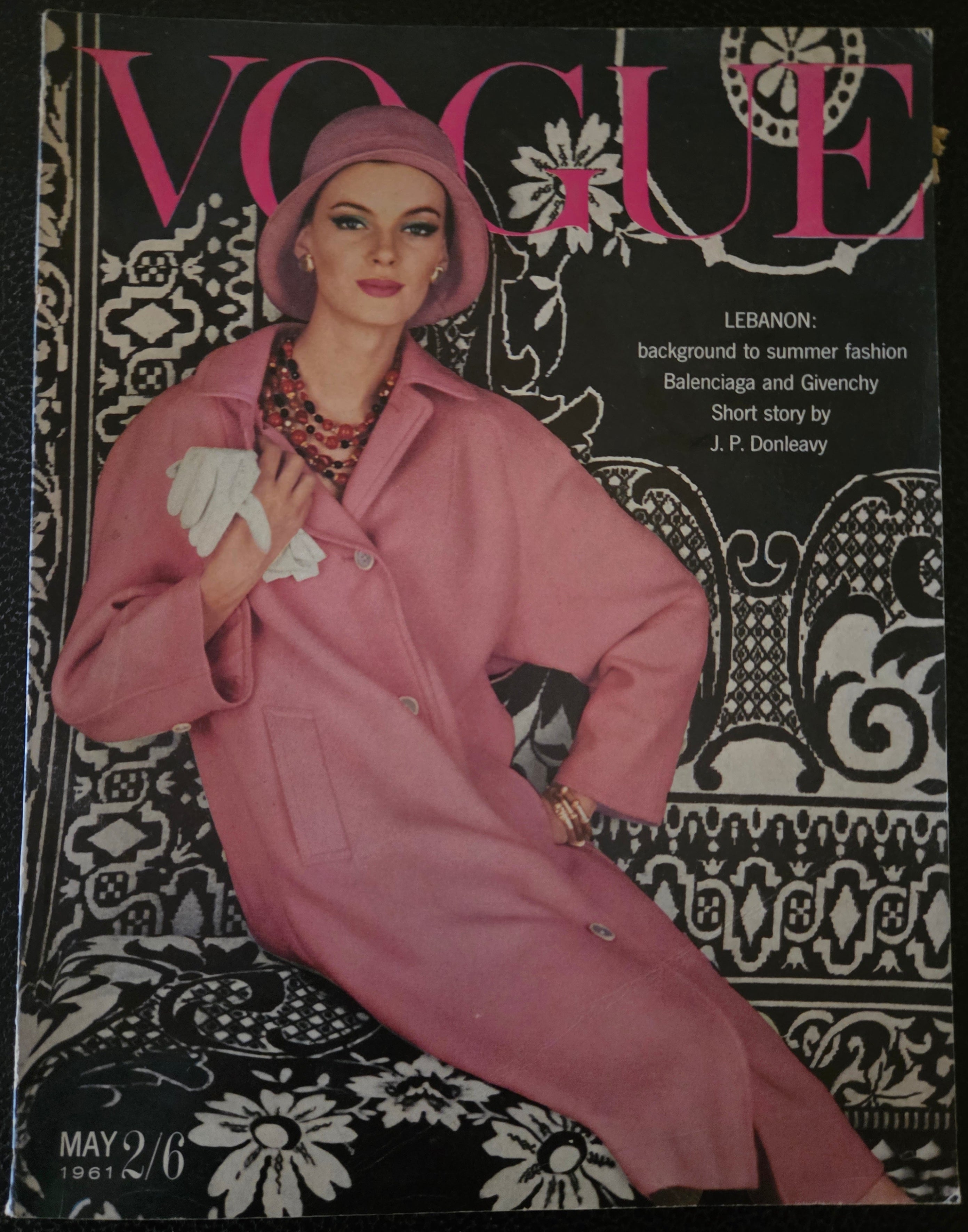Vintage Vogue magazine cover with a model in a pink coat on a decorative background