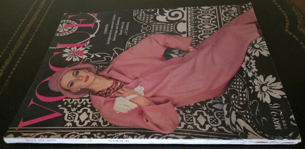 Vogue magazine cover with a model in a pink coat on a dark surface