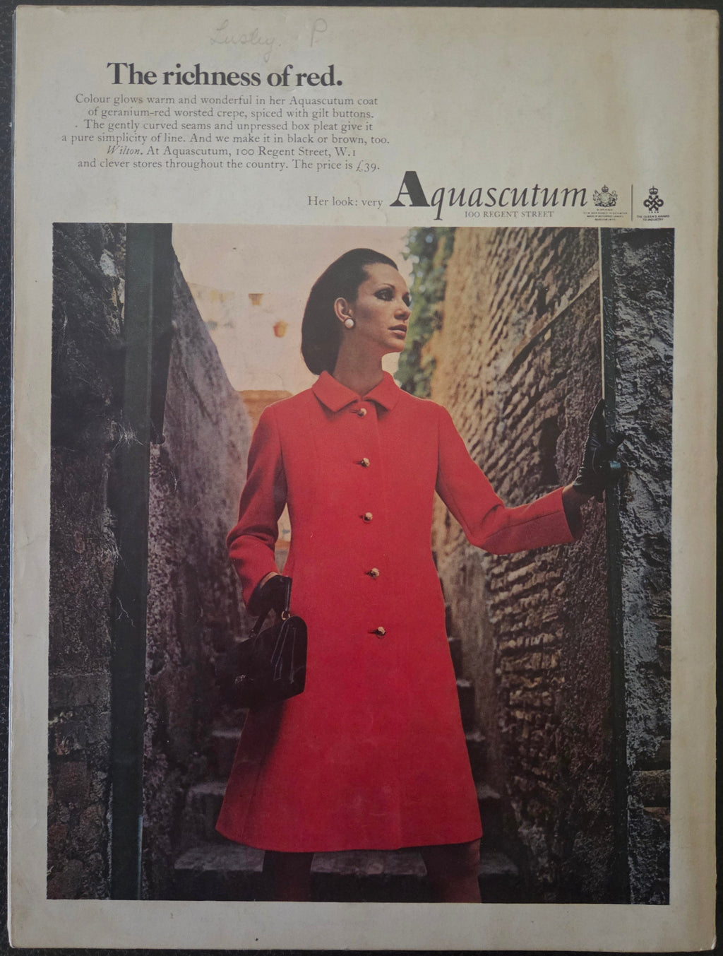 Vintage Aquascutum advert with model in red coat with black gloves and black handbag.