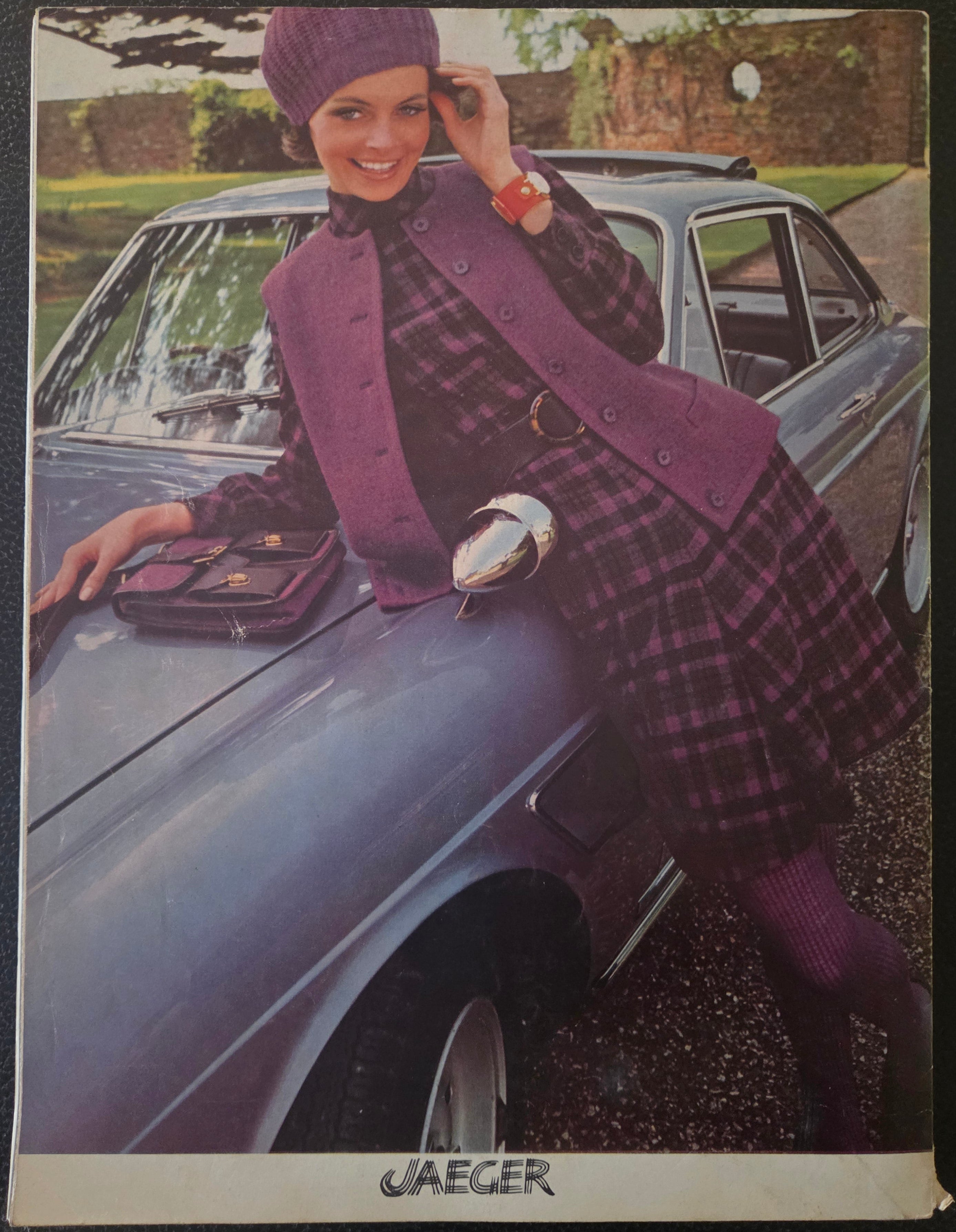 Vintage Jaeger advert with model in purple outfit leaning on car.