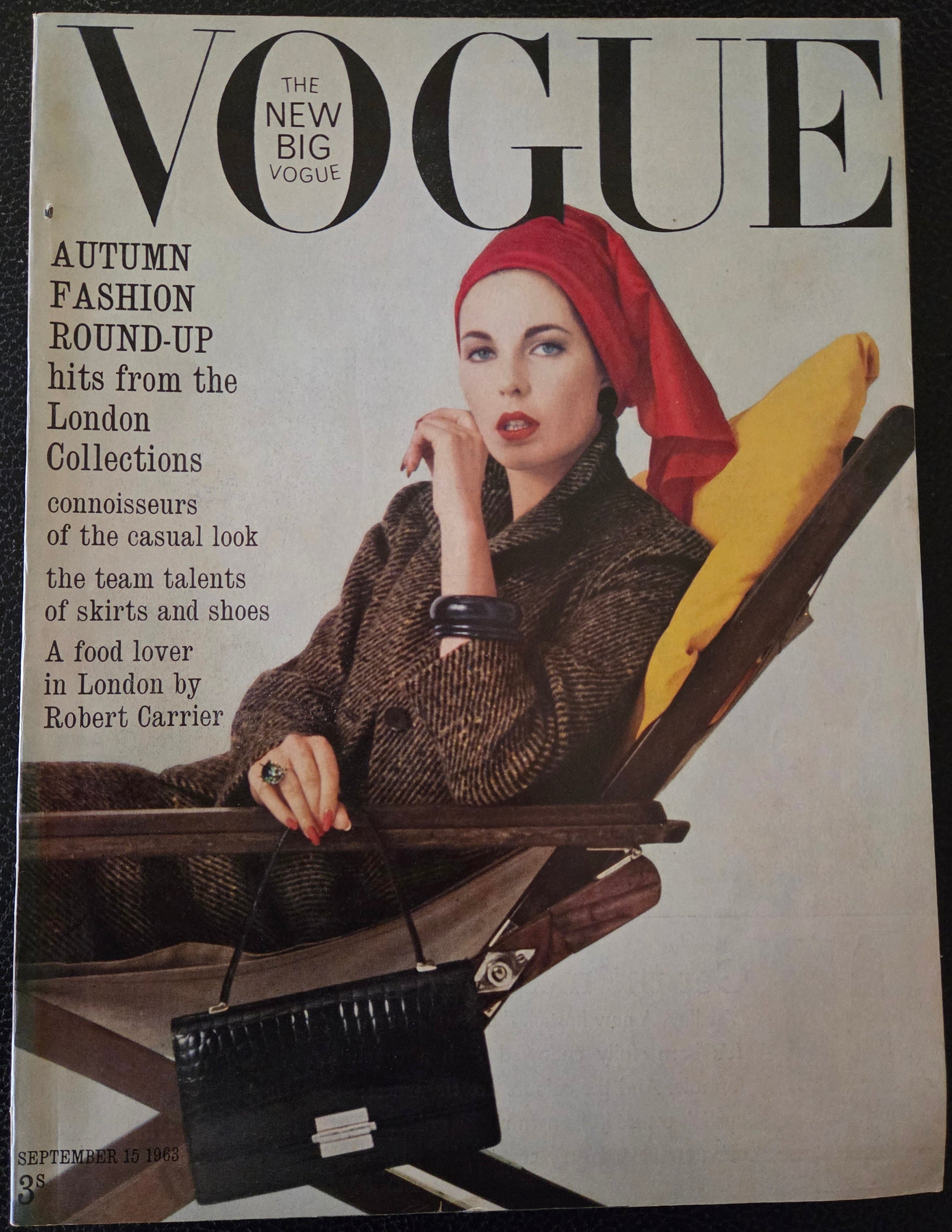 Vogue magazine cover with a model wearing a red headscarf and brown outfit.