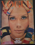 Magazine cover with a close-up of a person's face surrounded by colorful accessories.