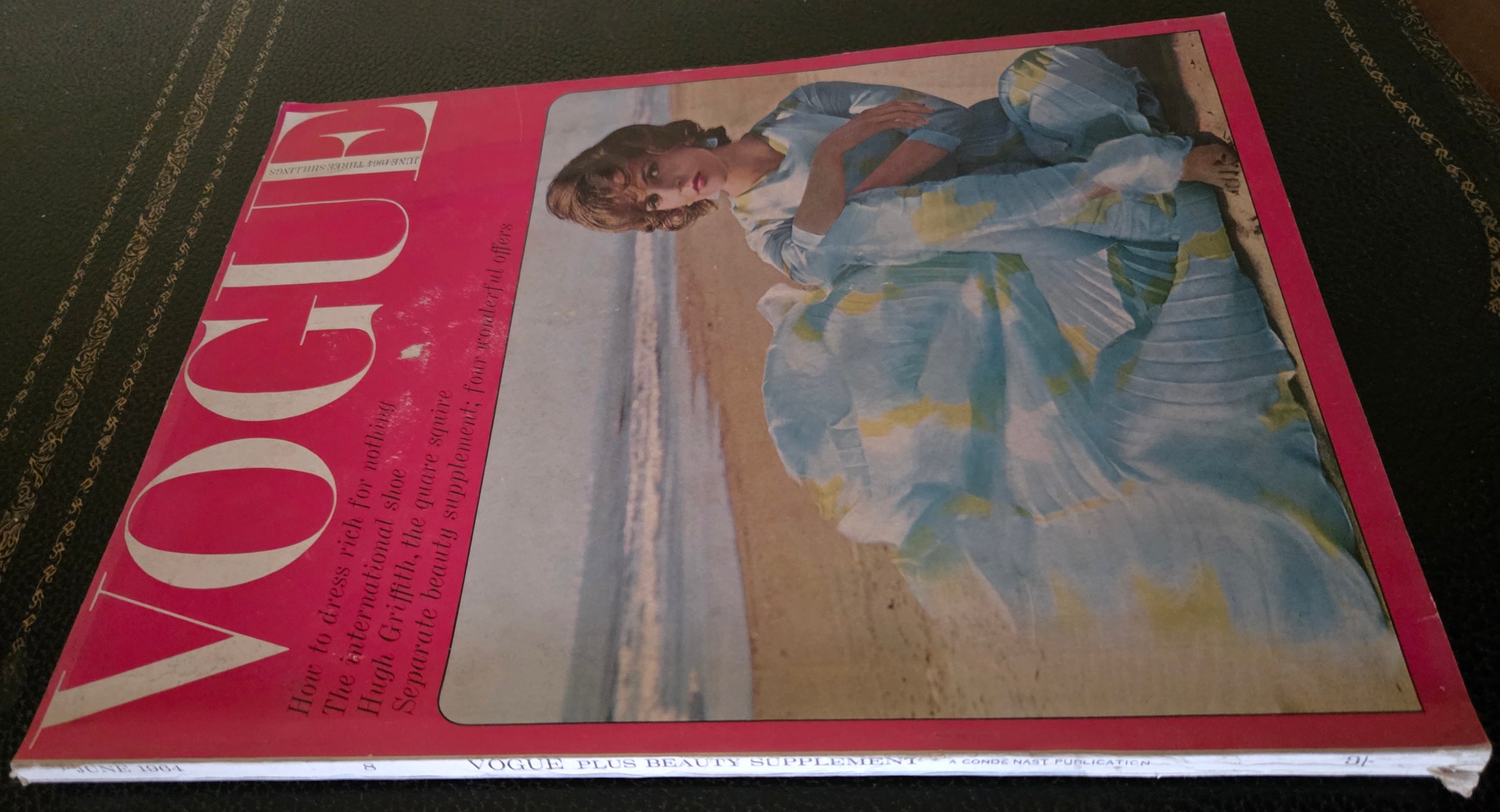Vintage Vogue magazine cover with a woman in a dress on a beach